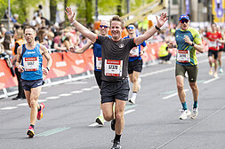 GENERALI BERLIN HALF MARATHON: A happy runner throws his hands up shortly before the finish of the GENERALI BERLIN HALF MARATHON 2024.© SCC EVENTS // Jean-Marc Wiesner