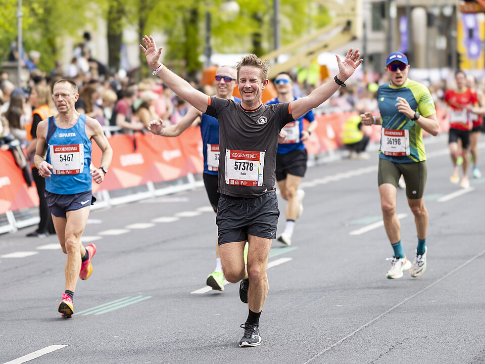 GENERALI BERLIN HALBMARATHON: Ein glücklicher Läufer reißt kurz vor dem Ziel des GENERALI BERLINER HALBMARATHON 2024 die Hände hoch. © SCC EVENTS // Jean-Marc Wiesner