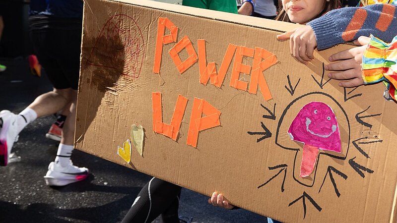 Selbstgebasteltes Pappschild mit den Worten "Power Up" aufgedruckt.