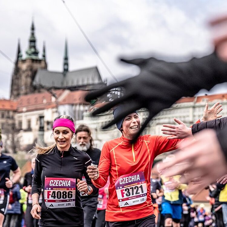 Two smiling runners wave to the crowd at the Prague Half Marathon.