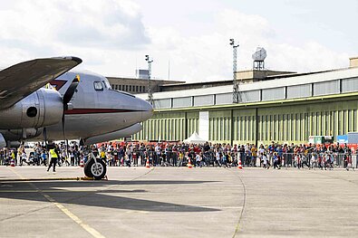 GENERALI BERLIN HALF MARATHON 2024: Spectators at the exhibition grounds of the former Tempelhof Airport cheer on Bambinis during the race, in the foreground a raisin bomber © SCC EVENTS / Jean Marc Wiesner