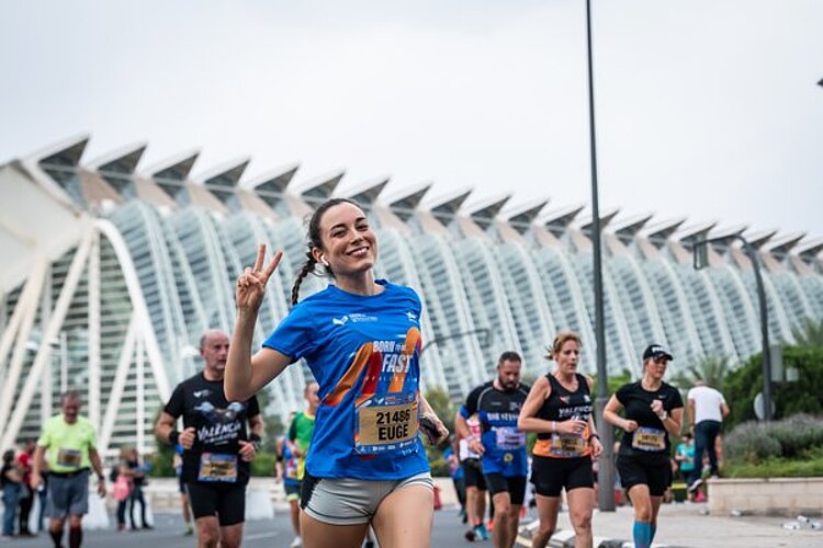 A smiling runner making a victory sign in front of the Ciutat de les Arts i les Ciències.