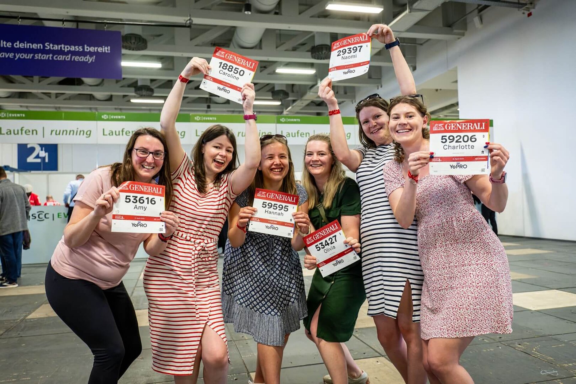 Lachende Frauengruppe posiert mit ihren Startnummern.
