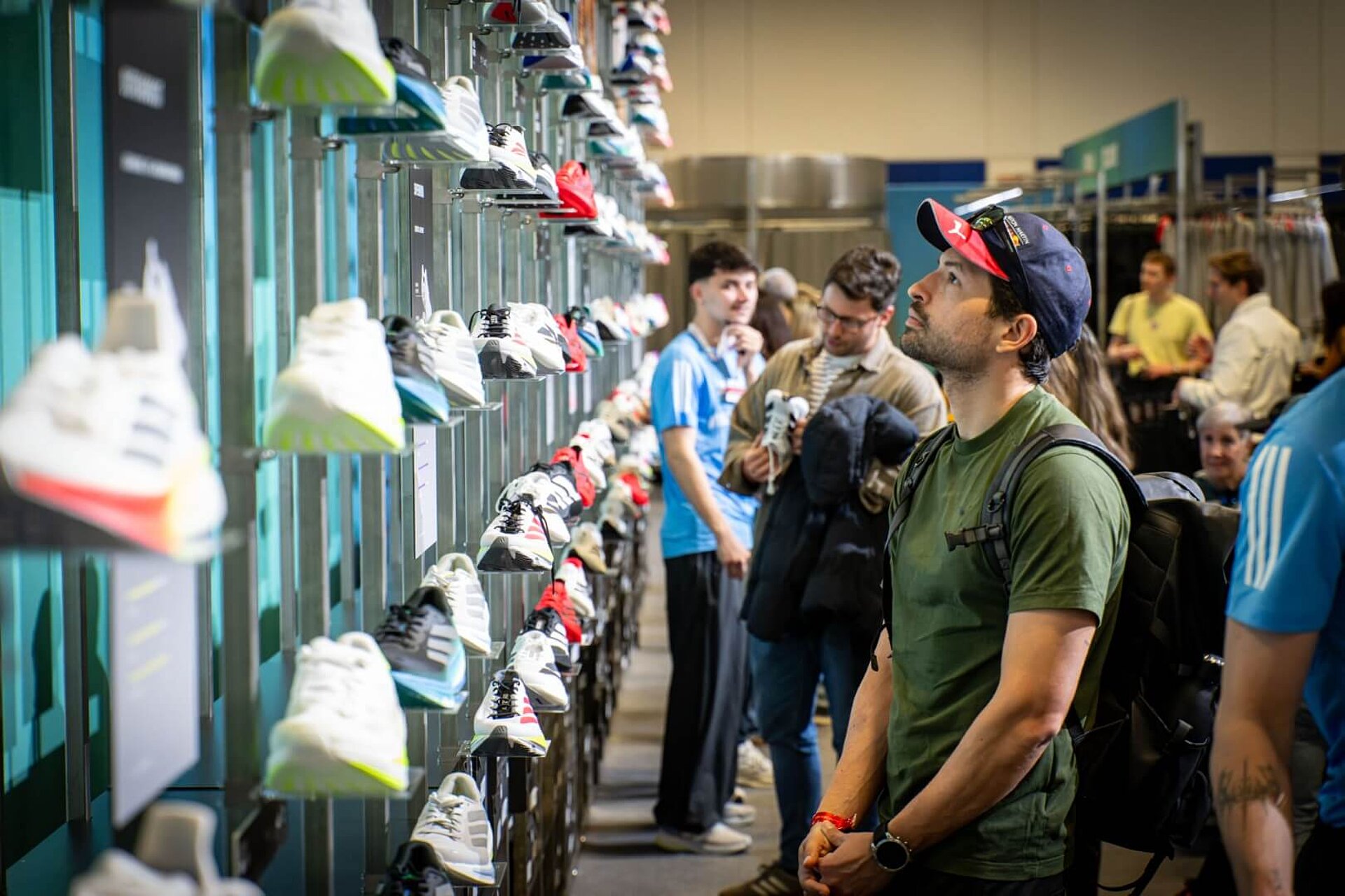 Mann begutachtet Schuhe an Wand am Adidas-Stand.