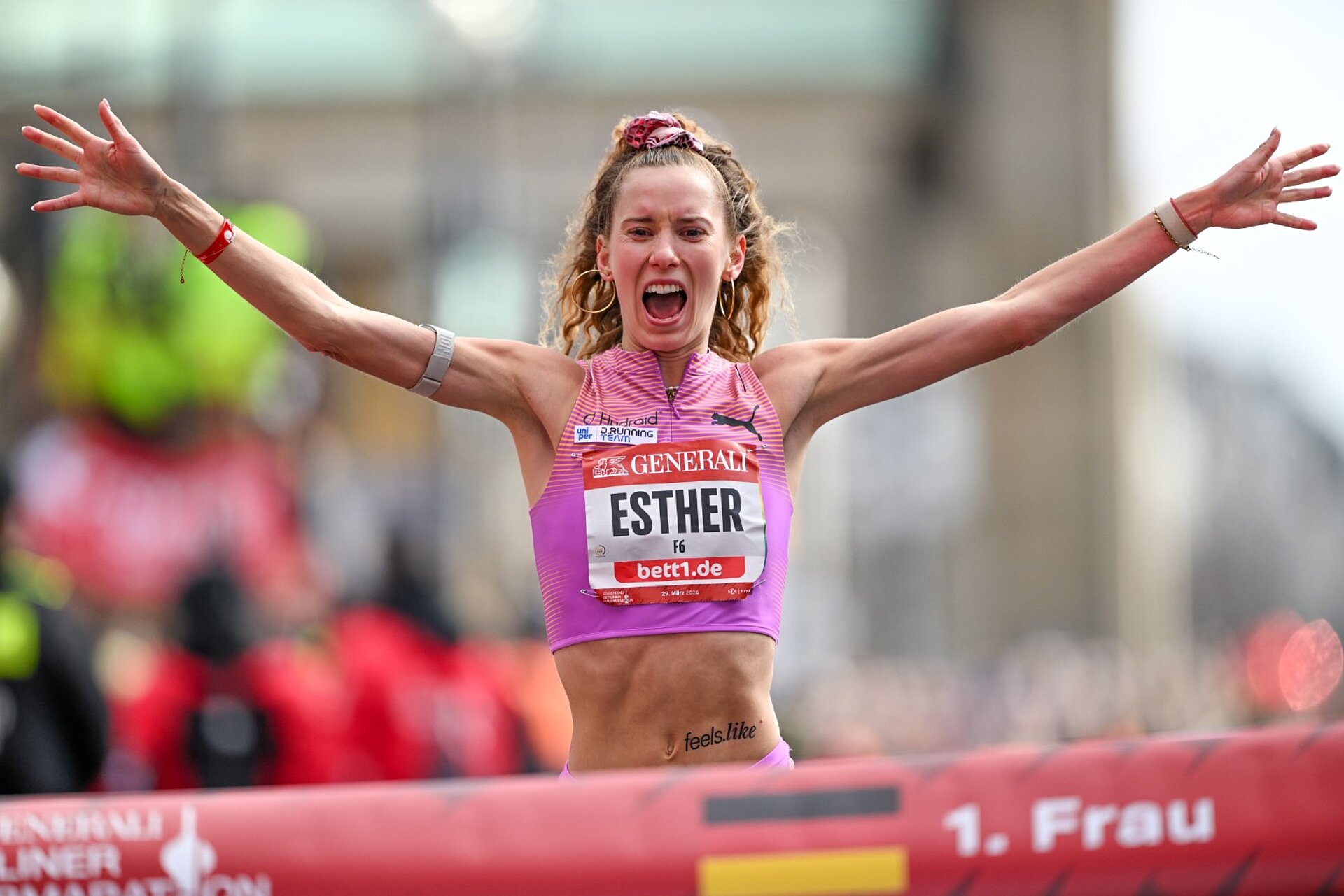Esther Pfeiffer, arms thrown up in the air and shouting with joy, just before crossing the finish line as the first German woman.