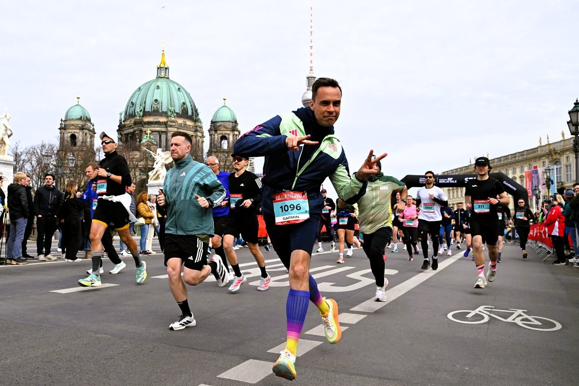 Ein Läufer zeigt kurz nach dem Start zwei Peace-Zeichen mit den Fingern in die Kamera.