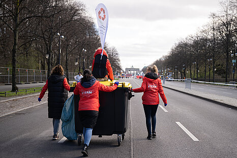 GENERALI BERLIN HALF MARATHON: Team members collect thermal foil and push the storage garbage can towards the Brandenburg Gate © SCC EVENTS / Annegret Hilse