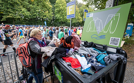 GENERALI BERLIN HALF MARATHON: Spectator donates clothes and puts them in a garbage can © SCC EVENTS / Thilo Wiedensohler