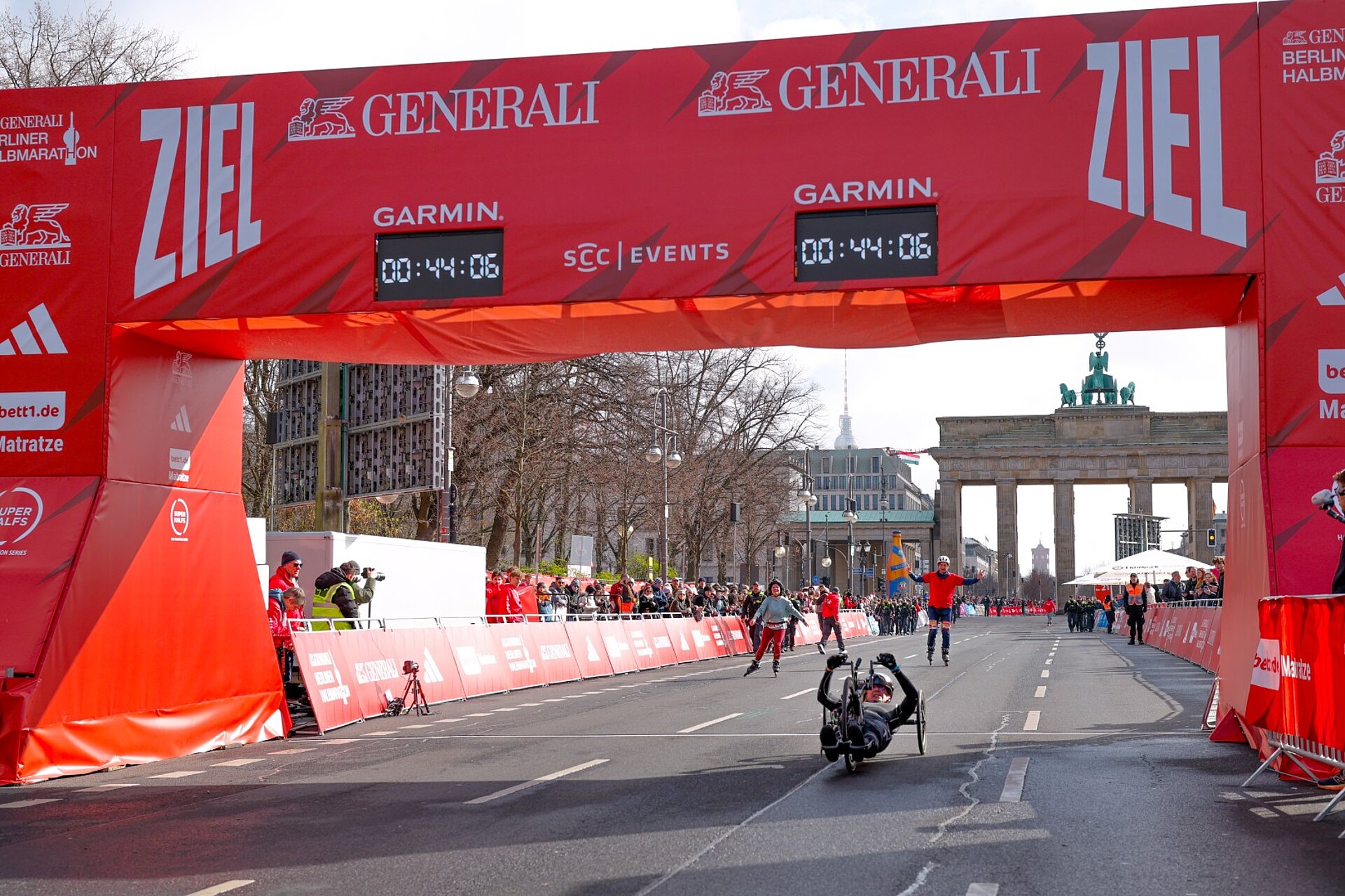 Mathias Behr crosses the finish line with his hands on the pedals. The clock reads 00:44:06.