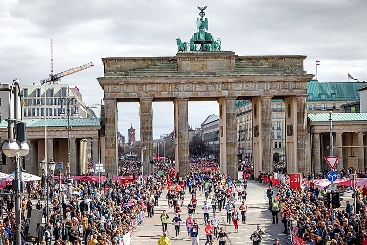 A bird's-eye view of the runners crossing the finish line in front of the Brandenburg Gate.