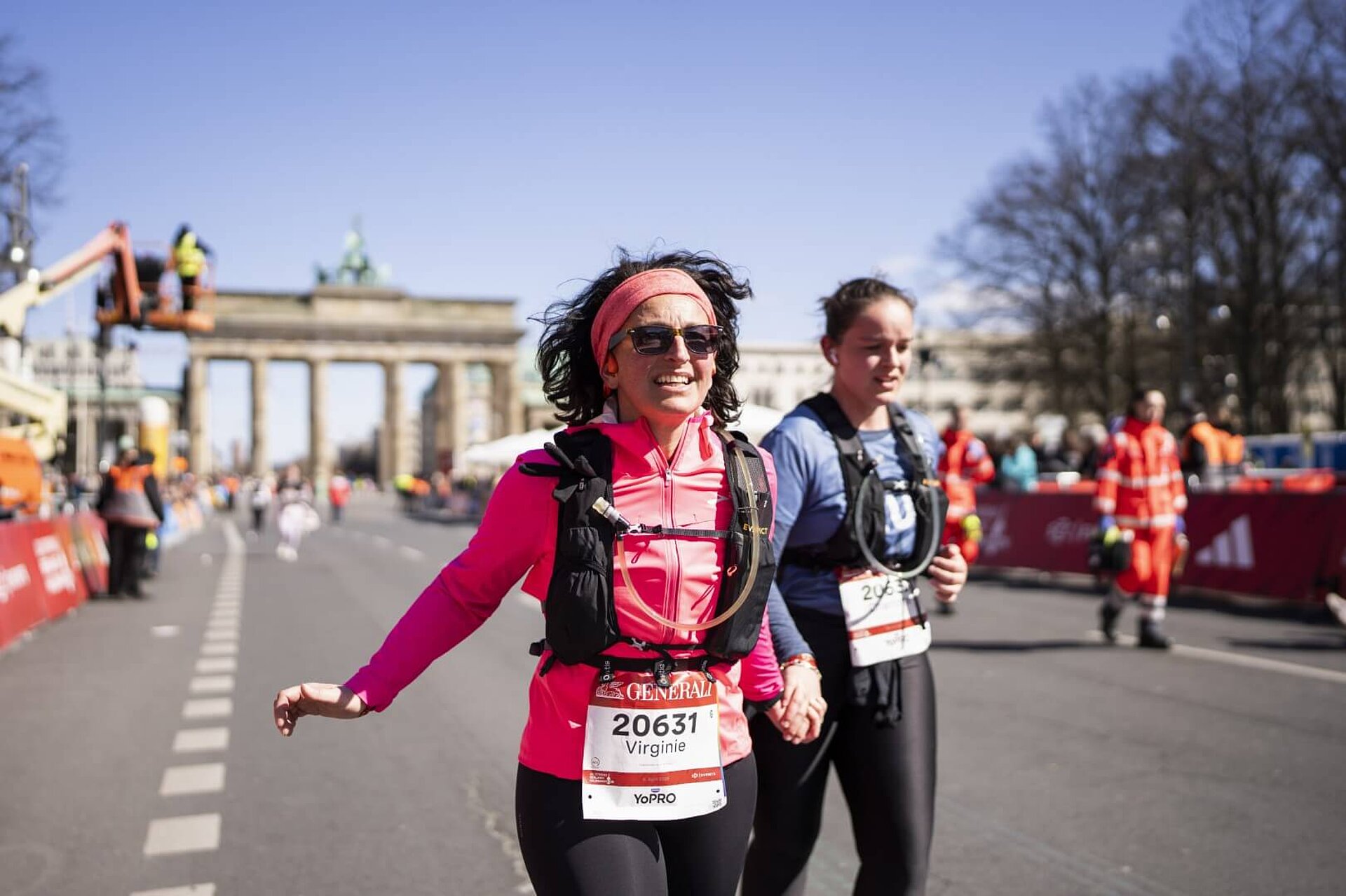 Zwei Läuferinnen mit Trinkrucksack auf der Zielgeraden hinter dem Brandenburger Tor.