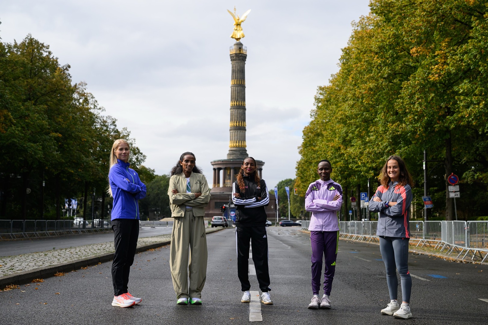 Von links nach rechts: Alisa Vainio, Dera Dida, Tigst Assefa, Rosemary Wanjiru und Manon Trapp posieren auf der Straße des 17. Juni mit Siegessäule im Hintergrund.